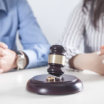 Gavel and wedding ring with blurred background of two couples