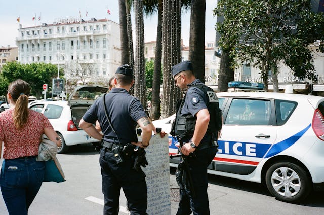 Police officers stand near a car in front of a building in New Jersey, a stop and ID state.