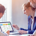 Three people are working and looking at a computer