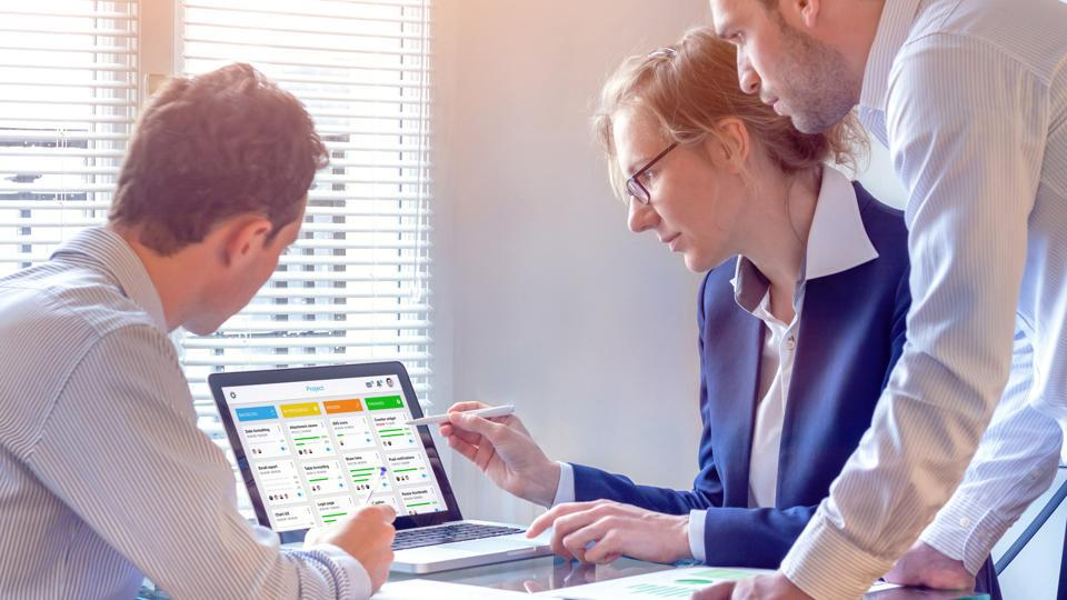 Three people are working and looking at a computer